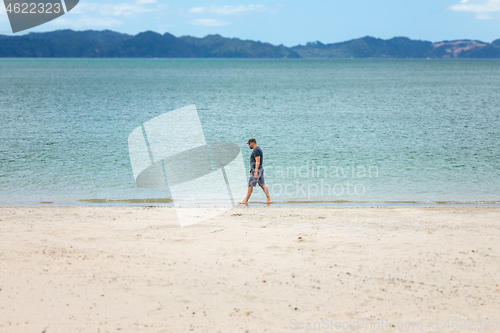 Image of man walking alone at the beach New Zealand