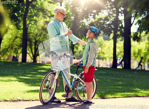 Image of grandfather and boy with bicycle at summer park