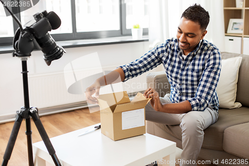 Image of male video blogger opening parcel box at home