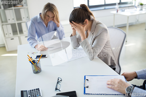 Image of stressed business team with papers at office