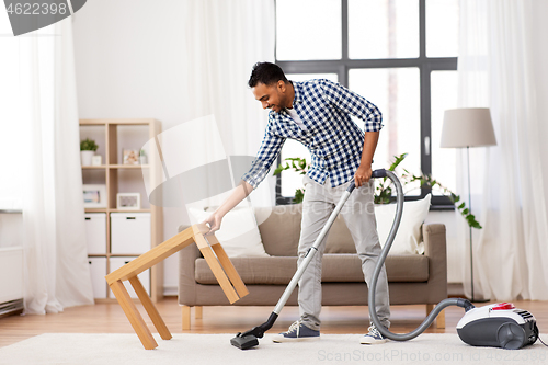 Image of indian man with vacuum cleaner at home