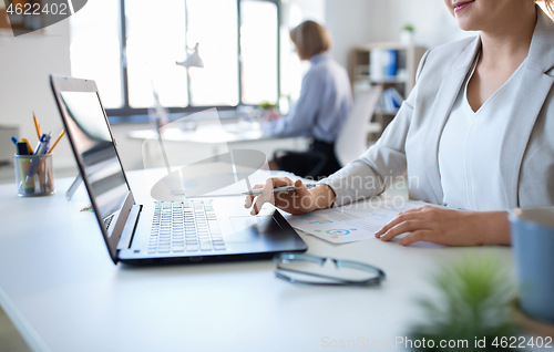 Image of businesswoman with laptop working at office