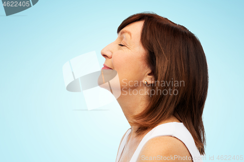 Image of profile of smiling senior woman over blue