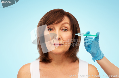 Image of senior woman and cosmetologist\'s hand with syringe