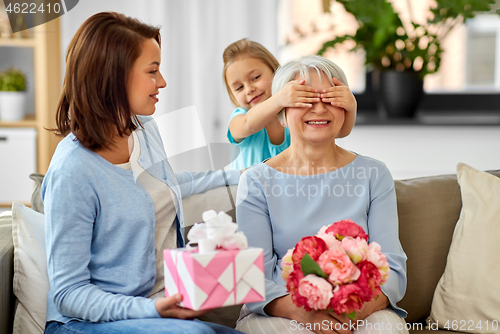 Image of mother and daughter greeting grandmother at home