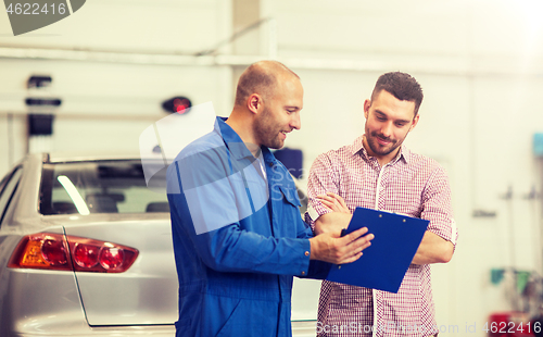 Image of auto mechanic with clipboard and man at car shop