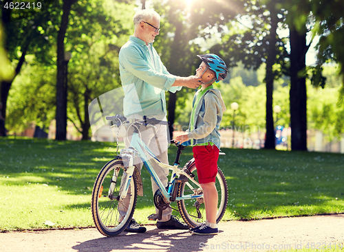 Image of grandfather and boy with bicycle at summer park