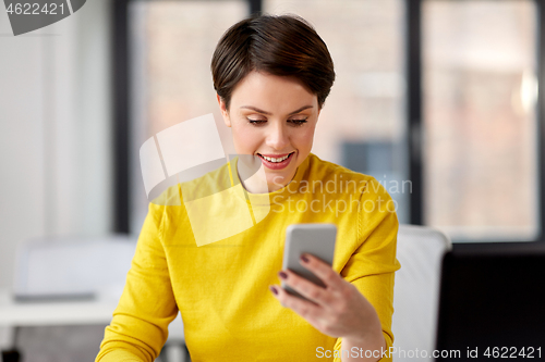 Image of businesswoman with smartphone working at office