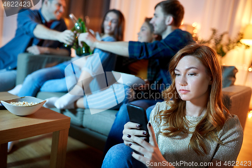 Image of sad young woman with smartphone at home party