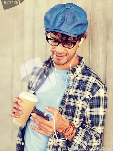 Image of man with earphones and smartphone drinking coffee