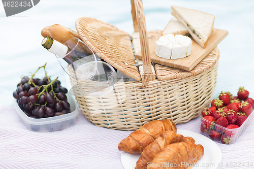 Image of picnic basket, food and wine glasses on blanket