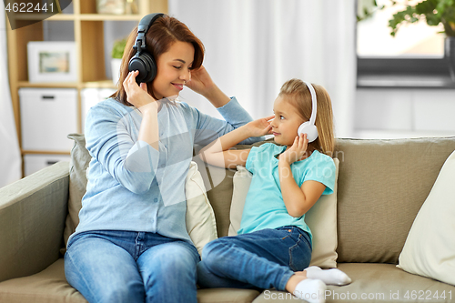Image of mother and daughter in headphones listen to music
