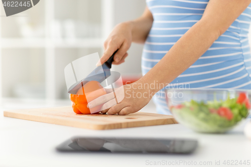 Image of pregnant woman cooking vegetable salad at home