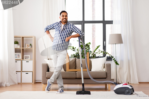 Image of indian man with vacuum cleaner at home