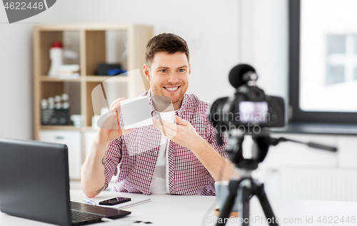 Image of male blogger with camera videoblogging at home