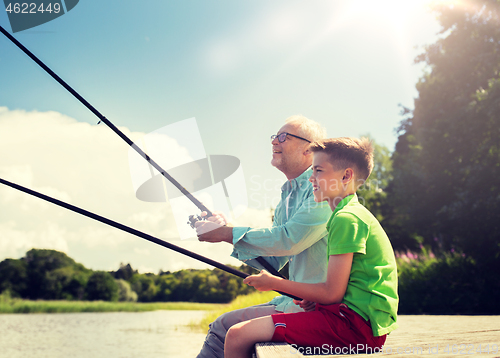 Image of grandfather and grandson fishing on river berth