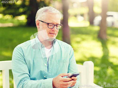 Image of happy senior man texting on smartphone at summer