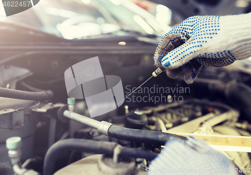 Image of mechanic with dipstick checking motor oil level
