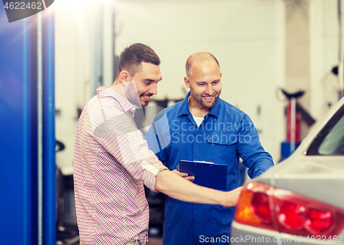 Image of auto mechanic with clipboard and man at car shop