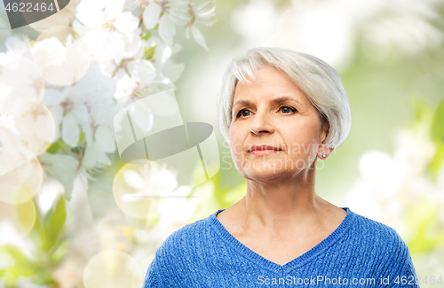 Image of portrait of senior woman in blue sweater over grey