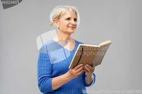 Image of senior woman with pencil and diary or notebook