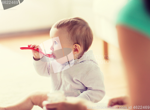 Image of mother and baby with spoon eating at home