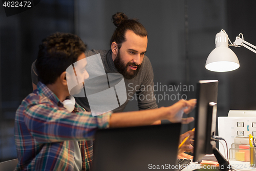 Image of creative team with computer working late at office