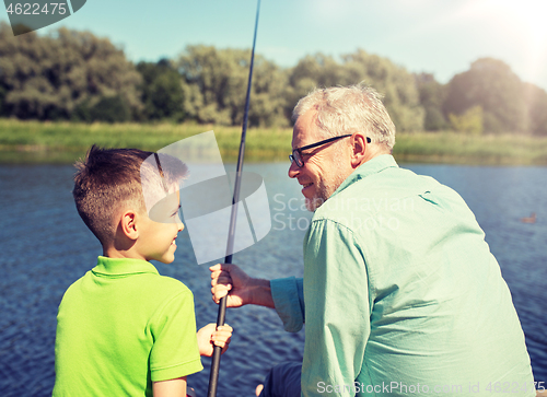 Image of grandfather and grandson fishing on river berth