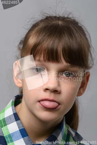 Image of Portrait of a ten-year-old girl sticking out her tongue from resentment, European appearance, close-up