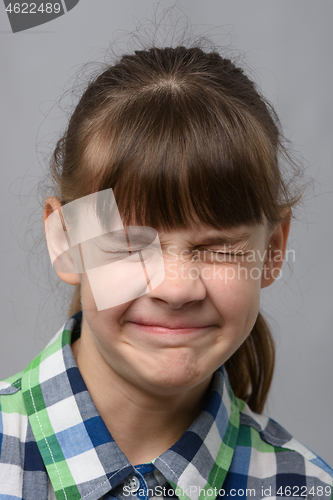 Image of Portrait of a ten-year-old girl squinting her eyes, European appearance, close-up
