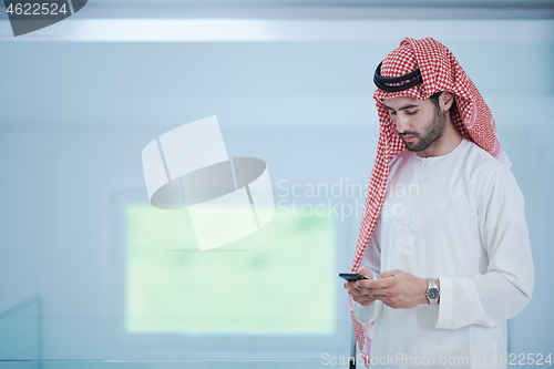 Image of young arabian businessman using smartphone at home