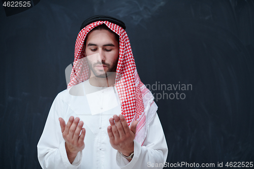 Image of arabian man making traditional prayer to God, keeps hands in pra