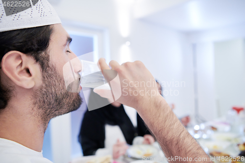 Image of Muslim family having Iftar dinner drinking water to break feast