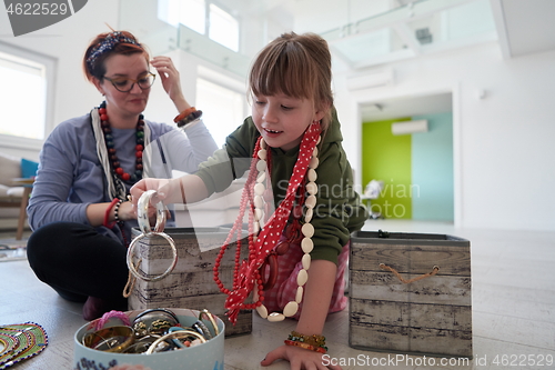 Image of Mother and little girl daughter playing with jewelry  at home