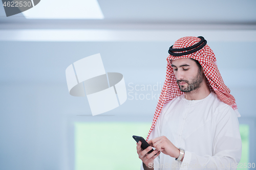 Image of young arabian businessman using smartphone at home