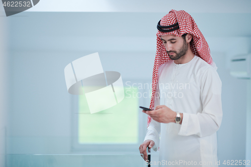 Image of young arabian businessman using smartphone at home