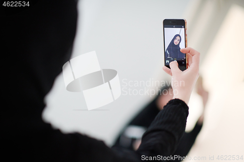 Image of muslim woman taking selfie picture at home