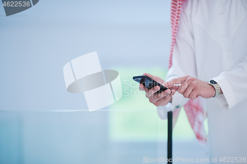 Image of young arabian businessman using smartphone at home