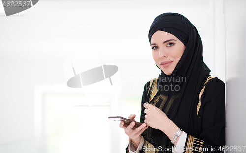 Image of young modern muslim business woman using smartphone at home