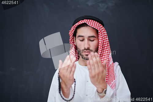 Image of arabian man making traditional prayer to God, keeps hands in pra