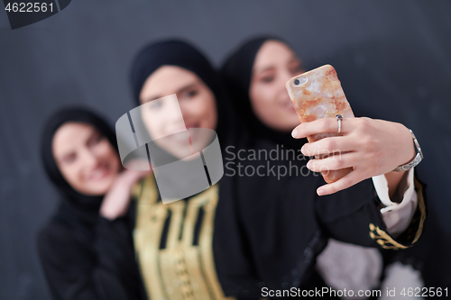 Image of muslim women taking selfie picture in front of black chalkboard