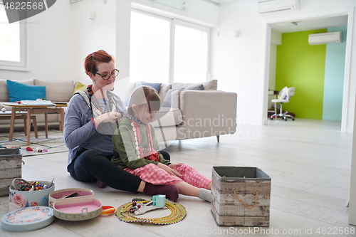 Image of Mother and little girl daughter playing with jewelry  at home