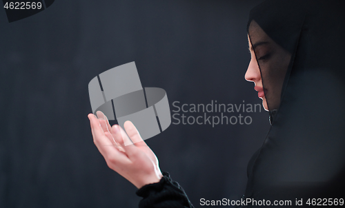 Image of muslim woman making traditional prayer to God in front of black 