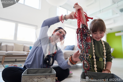 Image of Mother and little girl daughter playing with jewelry  at home