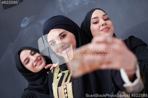 Image of muslim women taking selfie picture in front of black chalkboard