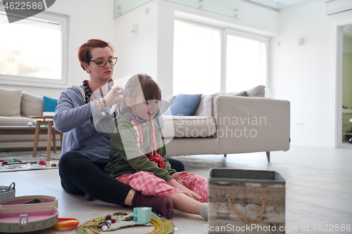 Image of Mother and little girl daughter playing with jewelry  at home