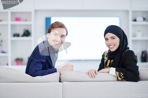 Image of young muslim couple watching TV together