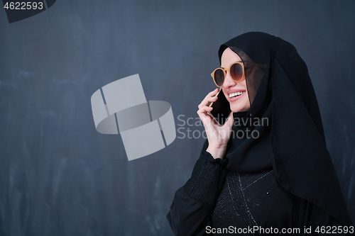 Image of young muslim woman wearing sunglasses using smartphone