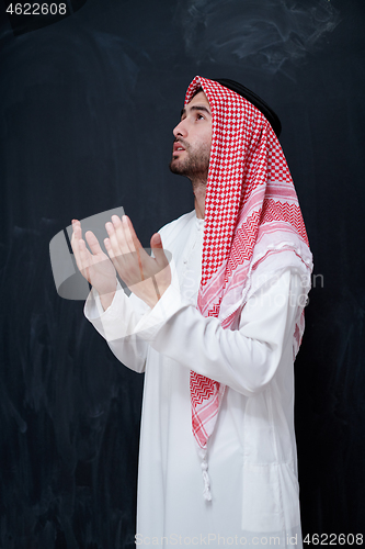 Image of arabian man making traditional prayer to God, keeps hands in pra