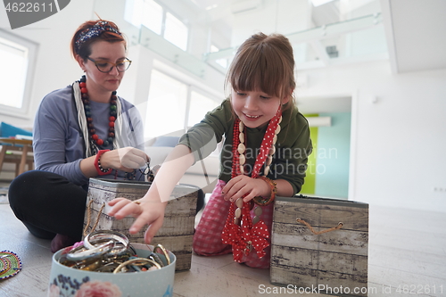 Image of Mother and little girl daughter playing with jewelry  at home